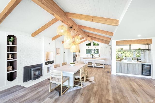 dining area featuring a wood stove, wine cooler, light wood finished floors, and vaulted ceiling with beams