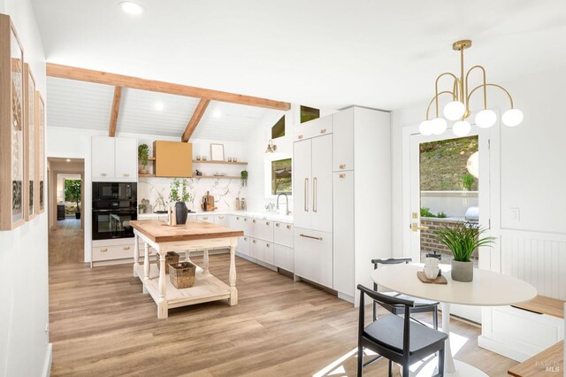 kitchen featuring vaulted ceiling with beams, open shelves, backsplash, a sink, and light wood-type flooring