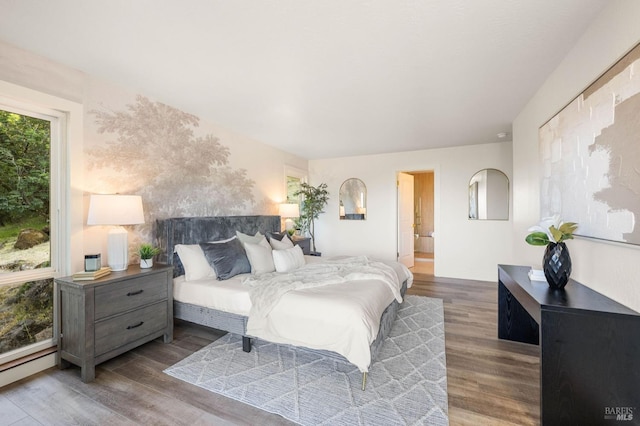 bedroom featuring wood finished floors and a baseboard heating unit