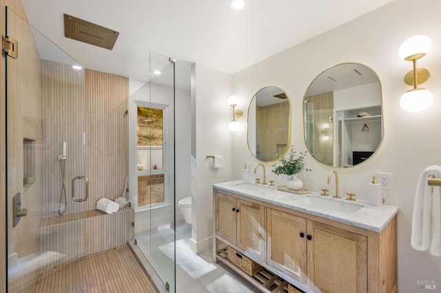 bathroom featuring a stall shower, toilet, double vanity, and a sink