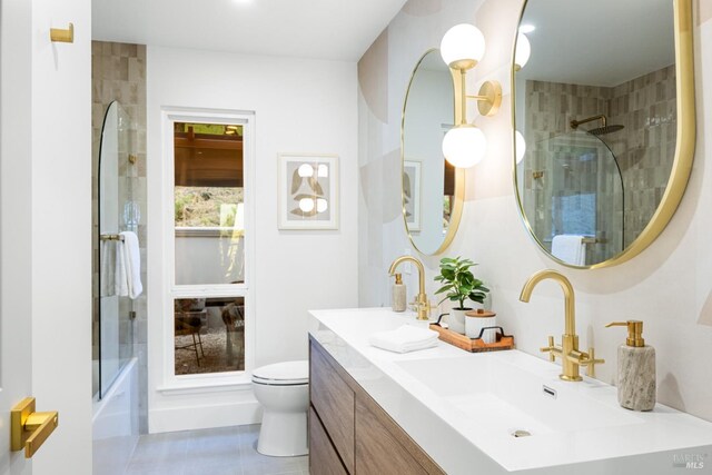 bathroom featuring tile patterned floors, toilet, double vanity, and a sink