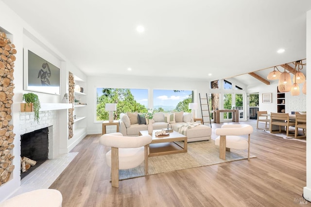 living area with recessed lighting, a wealth of natural light, light wood-style floors, and a brick fireplace