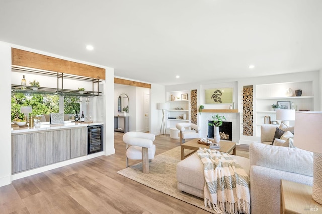 living area featuring recessed lighting, a fireplace, light wood finished floors, wet bar, and wine cooler