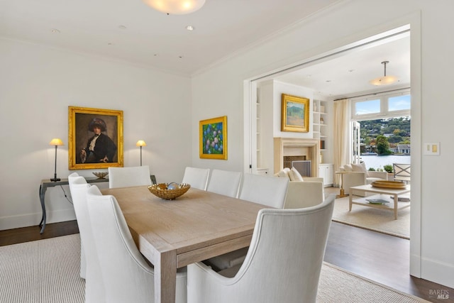72 Lagoon Rd, Belvedere, CA 94920 - dining space featuring wood finished floors, ornamental molding, built in shelves, a fireplace, and baseboards