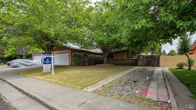 view of front of house with a front yard, a garage, driveway, brick siding, and fence