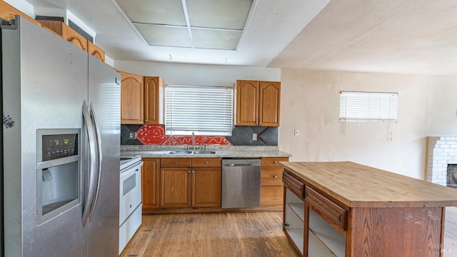 kitchen with a sink, appliances with stainless steel finishes, plenty of natural light, butcher block countertops, and light wood finished floors