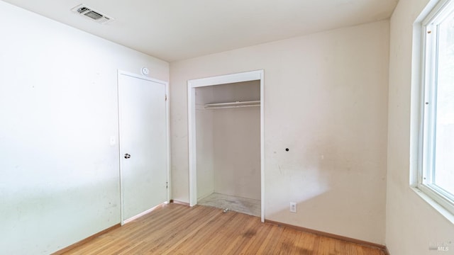unfurnished bedroom with visible vents, baseboards, light wood-style flooring, and a closet