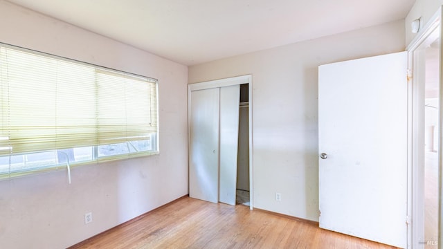 unfurnished bedroom featuring light wood finished floors and a closet