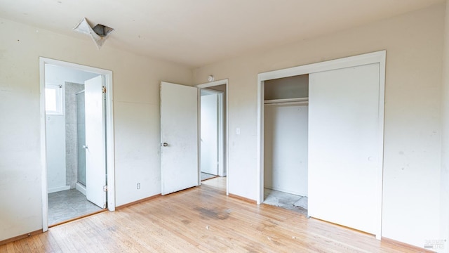 unfurnished bedroom featuring light wood-style floors, connected bathroom, baseboards, and a closet