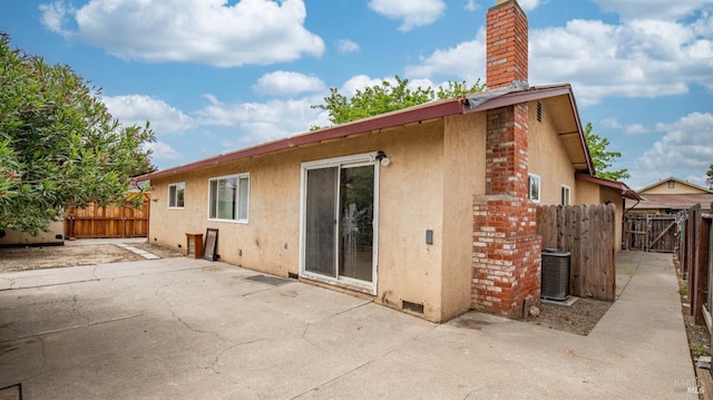 back of house featuring a patio area, central AC, a chimney, stucco siding, and fence
