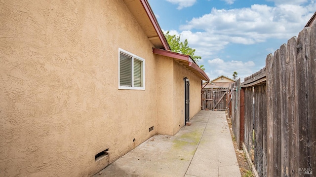 view of home's exterior with fence, stucco siding, and a patio area
