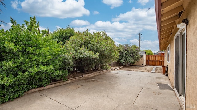 view of patio / terrace with a storage unit, a fenced backyard, and an outbuilding