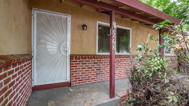 property entrance with brick siding and stucco siding