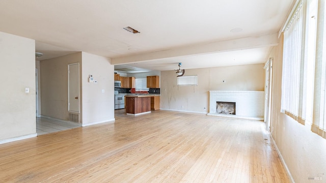 unfurnished living room with a fireplace, baseboards, and light wood-style floors