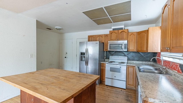 kitchen with a center island, light wood-type flooring, appliances with stainless steel finishes, and a sink