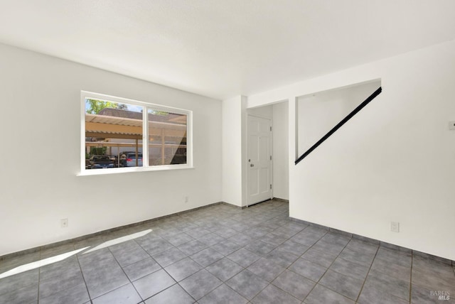 tiled empty room featuring baseboards