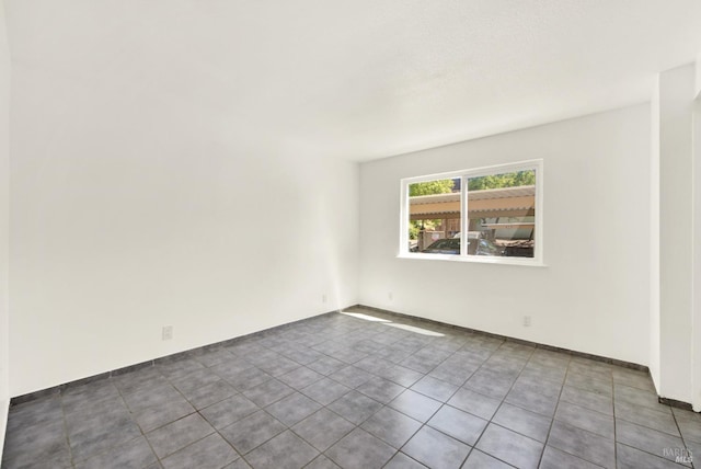 spare room with baseboards and tile patterned flooring