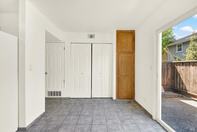 unfurnished bedroom featuring visible vents, light tile patterned floors, and a closet
