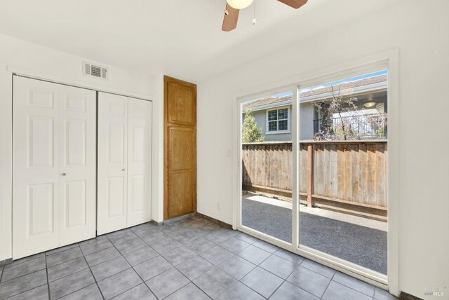 unfurnished bedroom with ceiling fan, visible vents, tile patterned flooring, baseboards, and a closet