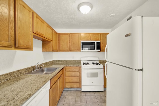 kitchen with a sink, white appliances, light countertops, a textured ceiling, and light tile patterned floors