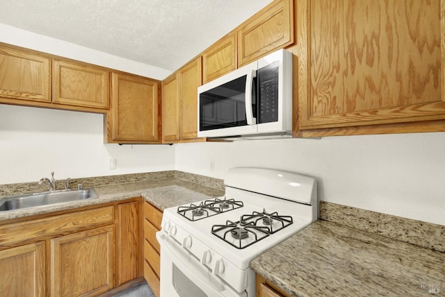kitchen featuring white appliances, a textured ceiling, and a sink