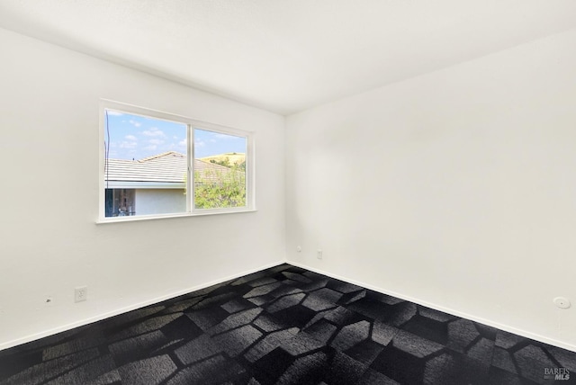 empty room featuring baseboards and dark colored carpet