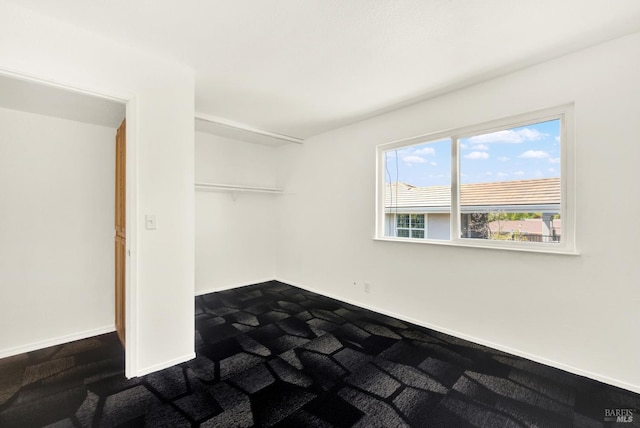 bedroom with baseboards, a closet, and dark colored carpet
