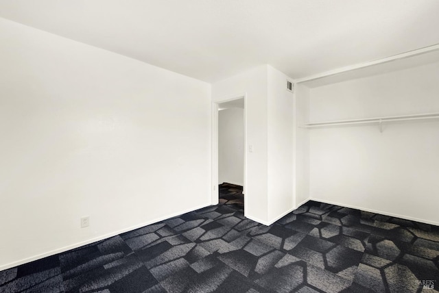 unfurnished bedroom featuring baseboards, visible vents, and dark colored carpet
