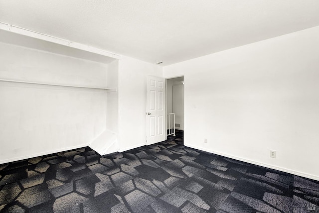 empty room featuring baseboards and dark colored carpet