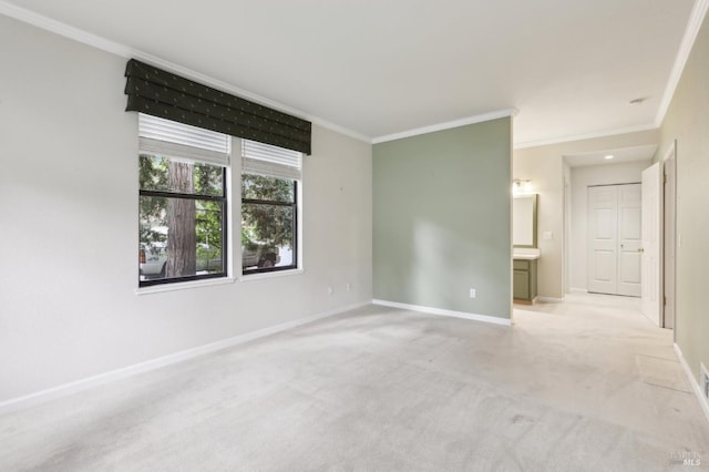 interior space featuring baseboards, ornamental molding, light colored carpet, and ensuite bathroom