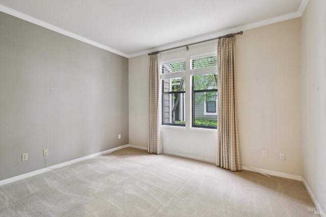 spare room with baseboards, ornamental molding, and light carpet