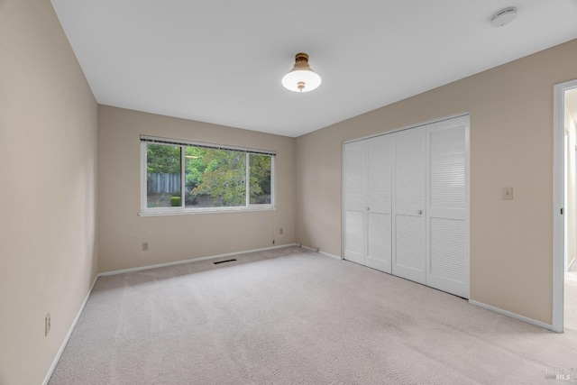 unfurnished bedroom featuring carpet floors, baseboards, a closet, and visible vents