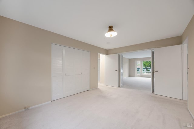 unfurnished bedroom featuring baseboards, light colored carpet, and a closet