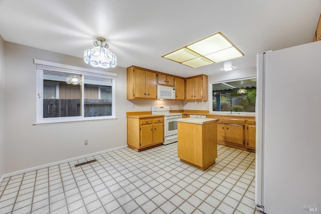 kitchen with a sink, white appliances, light countertops, baseboards, and a kitchen island