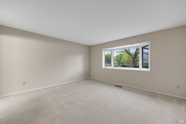 unfurnished room featuring baseboards, light carpet, and visible vents