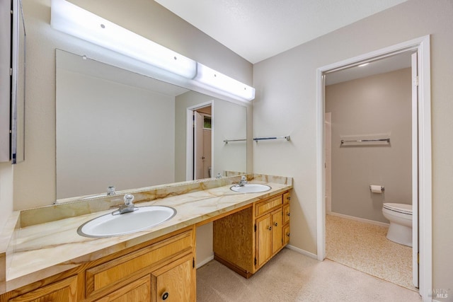 full bathroom with a sink, baseboards, toilet, and double vanity
