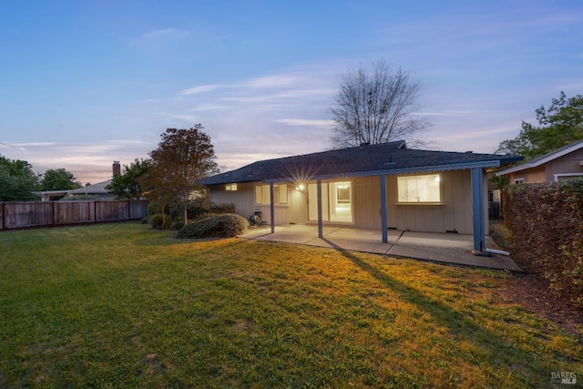 rear view of house featuring a yard, fence, board and batten siding, and a patio area