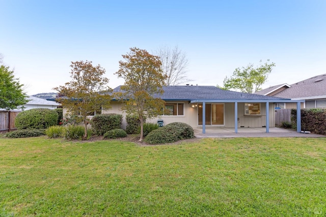 rear view of house featuring fence, a shingled roof, a yard, and a patio area