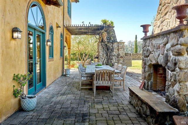 view of patio / terrace with a pergola, outdoor dining area, and an outdoor stone fireplace