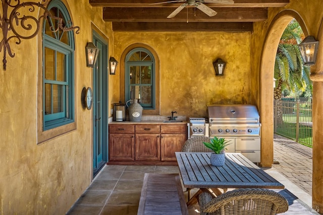 view of patio featuring fence, a ceiling fan, exterior kitchen, grilling area, and a sink