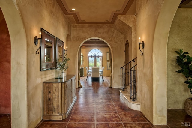 foyer with arched walkways, a textured wall, and stairway