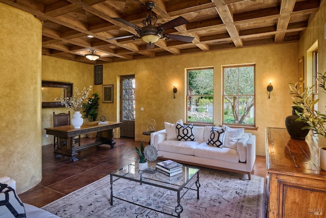 living area featuring coffered ceiling, a textured wall, a ceiling fan, and beam ceiling