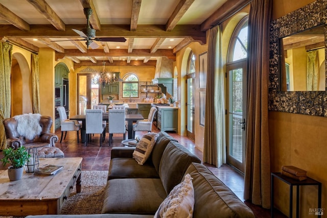 living area with arched walkways, ceiling fan with notable chandelier, and beamed ceiling