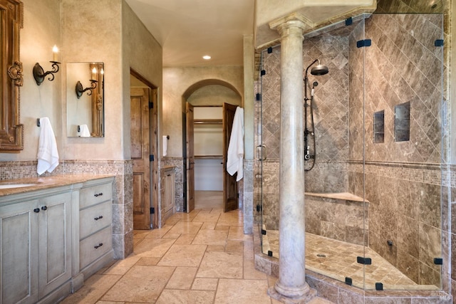 bathroom with stone tile flooring, vanity, tile walls, recessed lighting, and a shower stall