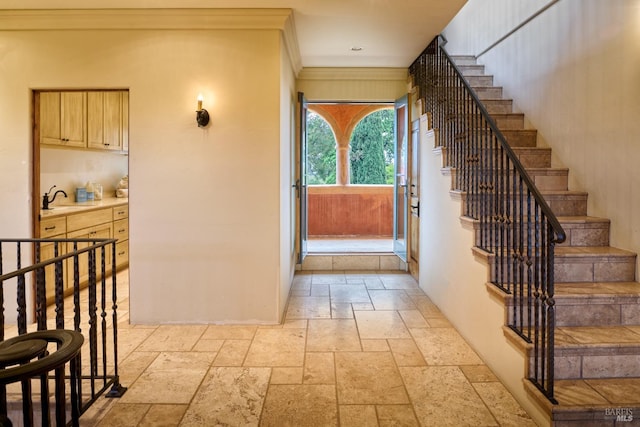 entryway with stairway, ornamental molding, and stone tile floors