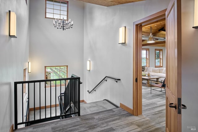 stairs with baseboards, an inviting chandelier, and a high ceiling