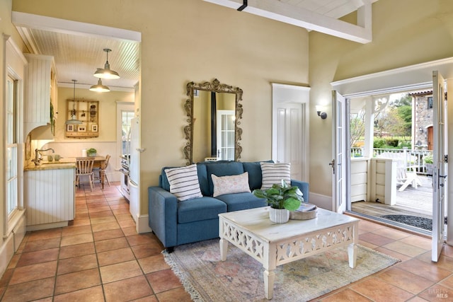 living room featuring ornamental molding, a towering ceiling, light tile patterned flooring, baseboards, and wood ceiling