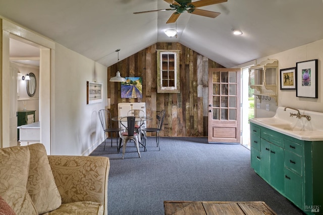 living area with ceiling fan, wood walls, carpet, and lofted ceiling