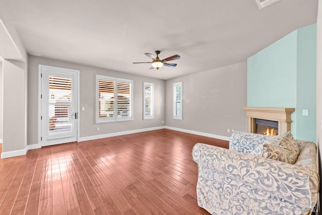living room featuring wood finished floors, baseboards, and ceiling fan