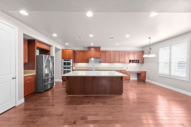 kitchen with recessed lighting, under cabinet range hood, light countertops, appliances with stainless steel finishes, and dark wood-style floors